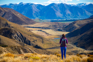 Fototapeta premium beautiful hiker girl enjoying the view from the top of trig m mountain in Torlesse Tussocklands Park, canterbury, new zealand south island