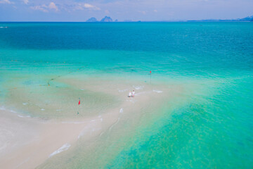 a couple of men and woman walking at a sandbar in the ocean of Koh Muk Thailand or Koh Mook