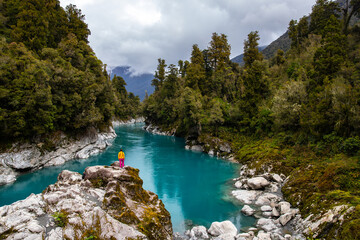 woman sitting on the rocks and enjoying unique blue water in hokitika gorge, west coast of new...
