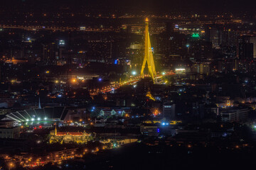 Aerial view of the city during the evening with a golden suspension bridge and buildings with beautiful lights in Bangkok, Thailand.