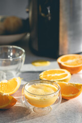 A glass of freshly squeezed orange juice and oranges on the kitchen table.