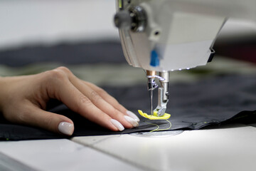female dressmaker working on the factory using sewing machine close up shot