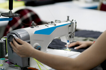 female dressmaker working on the factory using sewing machine close up shot