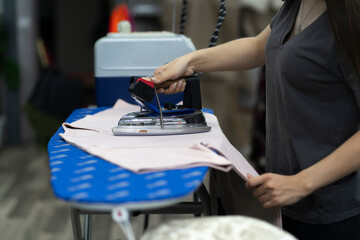 a clothing factory, seamstress ironing new wear in workshop