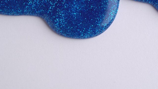 Blue glitter sparkle confetti background liquid drops of paint color flow down on yellow canvas. Blue glitter paint dripping on the white paper wall and filling the screen.