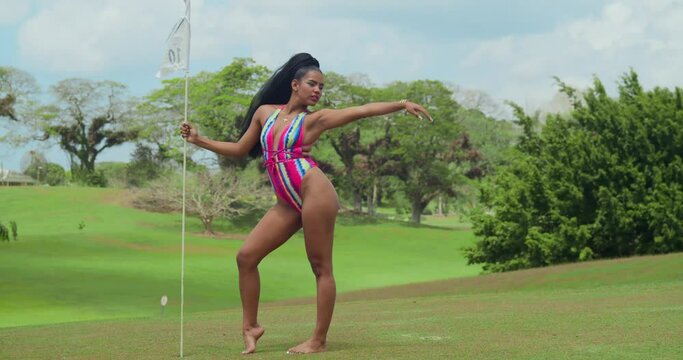 In the midst of a golf course in Trinidad, a girl in swimwear takes in the tropical beauty.