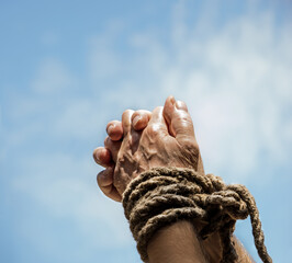 Rope tied hands on sky background