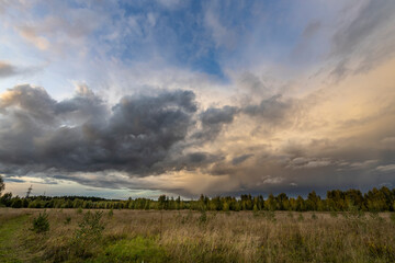 Fototapeta premium A thundercloud illuminated by the sun, low over a field