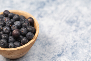 blueberries in a wooden bowl on a blue marble background, healthy food, fruit in a bowl