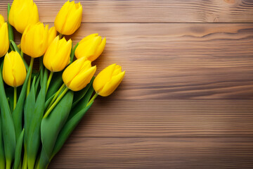 Bunch of yellow tulips on wooden surface.