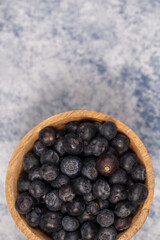blueberries in a wooden bowl on a blue marble background, healthy food, fruit in a bowl