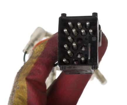 A old car connector or trailer for closing an electrical circuit that a mechanic holds in gloves during repairs.