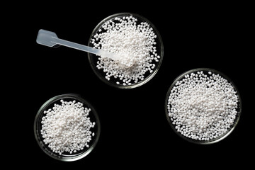 Top view of laboratory Petri dishes with samples of polymer plastic granules.