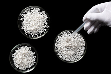 Close-up of a laboratory assistant conducting an experiment on polymer plastic granules.