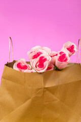 Bouquet of pink roses in paper bag on pink background. valentine's day background