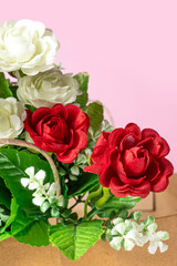Bouquet of red and white roses in box on pink background.