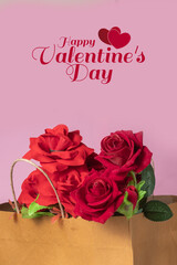Valentine's day greeting card with red roses in a brown paper bag on a pink background