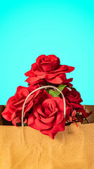 Beautiful bouquet of red roses in a paper bag on a blue background. close-up