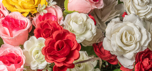 Close-up bouquet of beautiful artificial multicolored flowers as background.