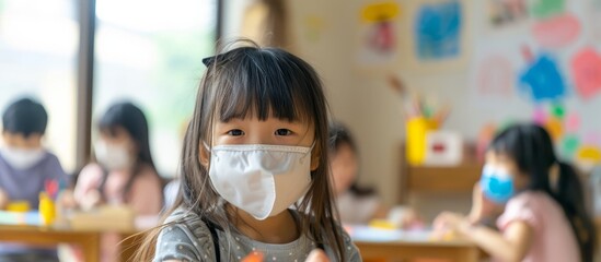 Asian girl wearing face mask takes art classes with children, painting and having fun with crafts at age 4.