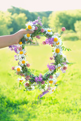 summer background. wreath of meadow flowers in hand outdoor. floral traditional decor for Summer...