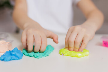 Girl playing with green and yellow slime at table