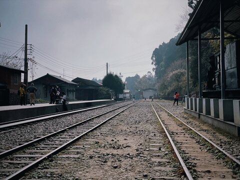 In the misty mountains, the train station features parallel railroad tracks stretching straight ahead.