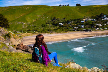 hiker girl enjoying a sunny day at godley head walkaway near christchurch, canterbury, new zealand;...