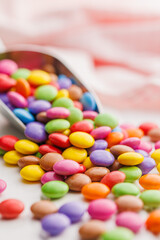 Colorful sweet candies in scoop on white table.