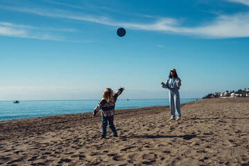 Mom plays frisbee with a boy in the sea. young woman and boy playing frisbee on the seashore....