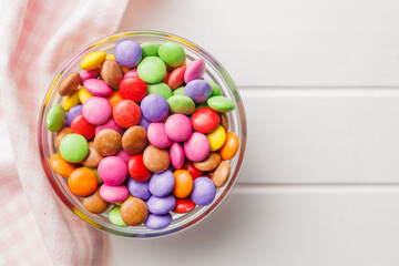 Colorful sweet candies in bowl on white table. Top view.