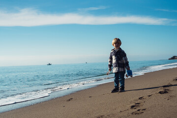 boy 3 years old blond plays on the seashore in the sand with pla - obrazy, fototapety, plakaty