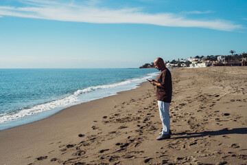 Man taking a picture with his phone. cheerful man takes pictures on his phone. positive emotion and mood. a man travels near the sea.