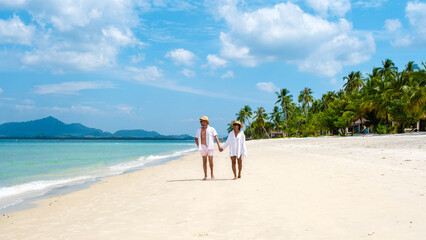 Fototapeta na wymiar Koh Mook a young couple of caucasian men and Thai Asian woman walking at the beach in Thailand