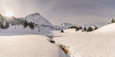 Panorama view with snowy mountains in Bregenzerwald, Austria, Körber lake with brown Arlberg peak...