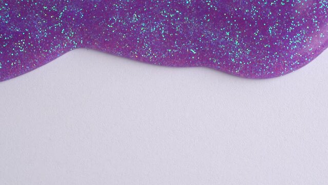 Lavender glitter sparkle confetti background liquid drops of paint color flow down on white canvas. Purple glitter paint dripping on the white wall and filling the screen.