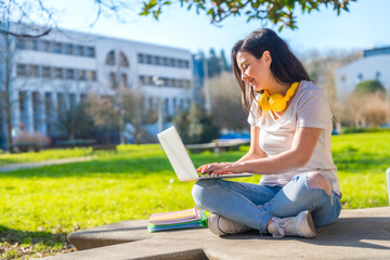 Woman studying using laptop sitting outside the campus
