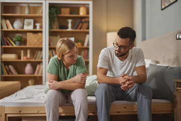 Young couple sitting on bed discussing marital problems