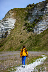 Naklejka na ściany i meble hiker girl enjoying a walk on kaikoura coast track in canterbury, new zealand; scenic track on famous peninsula with fur seal colony