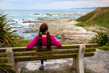 relaxed girl admiring the panorama of kaikoura peninsula from the top of a cliff; north canterbury,...