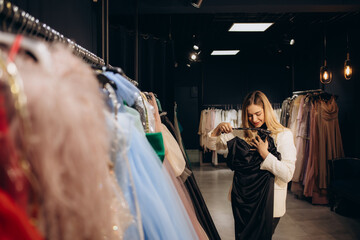 Beautiful happy young girl choosing clothes for high school prom in shop © Roman