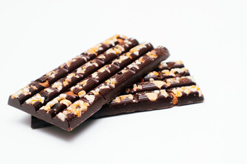 Dark chocolate bars with chopped nuts on a white background, side view. Dessert food. Dark chocolate in Pieces.