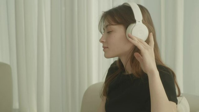 Young Woman Sitting on Couch Listening to Music and Relaxing at Home