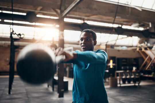 Smiling young man swinging a kettlebell during a gym workout
