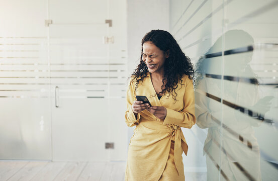 Businesswoman laughing at a text during a work break in an office
