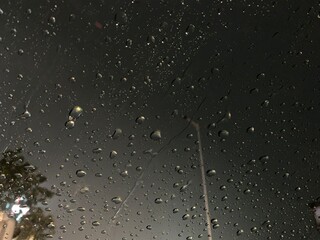 Rain drops on window windshield jaw drop in city at night travel
