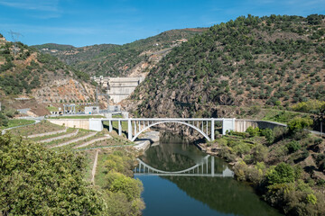 Fototapeta premium Harmonia Natural: A Ponte Sobre o Rio Tua entre Montes e Montanhas, com a Majestosa Barragem ao Fundo para Energia Sustentável