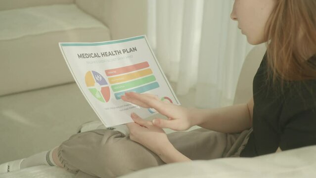 A young woman going over a medical health-plan document and nodding. indoors, daylight. 