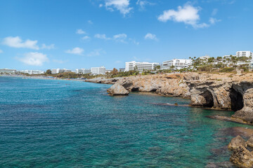 Vacation resort of Ayia Napa. A paradise for vacationers. A sunny day with a blue sky and white clouds. Panoramic view of the hotels, the blue lagoon and the coastline with rocks and caves. Cyprus. 