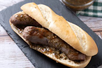 Traditional choripan, Argentina sandwich with chorizo and chimichurri sauce on wooden table